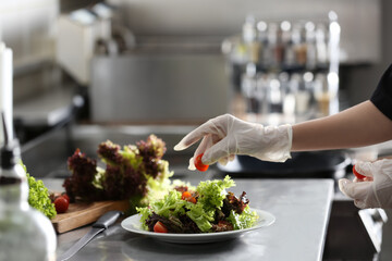 Obraz na płótnie Canvas Female chef cooking tasty food in restaurant kitchen, closeup