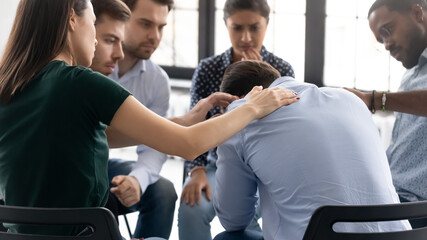Rear view diverse people comforting frustrated depressed man at meeting, helping overcoming...