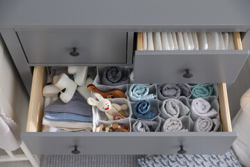 Modern open chest of drawers with clothes and accessories in baby room, above view
