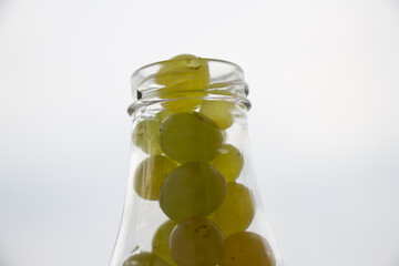 a bunch of white grapes in a glass against the sky.