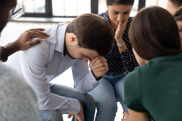 Close up depressed frustrated man feeling pain, getting psychological help at group counselling therapy session, diverse people sitting in circle, helping comforting upset despair patient