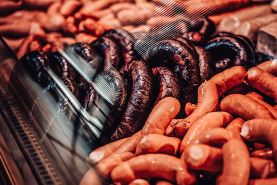 A fridgerator full-filled with many types of ham and sausages. Saling smoked meat. Butcher shop with huge choise of smoked meat.