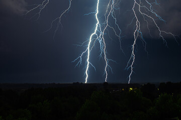 Lightning strike in the dark night sky. Summer thunderstorm.