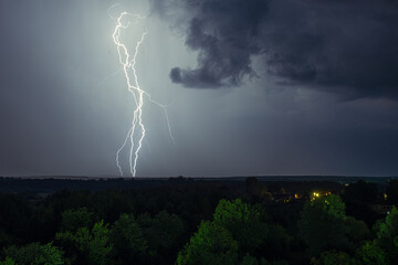 Lightning strike in the dark night sky. Summer thunderstorm.