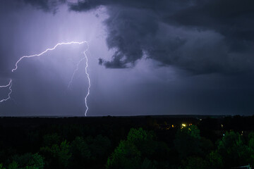 Lightning strike in the dark night sky. Summer thunderstorm.
