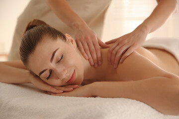 Young woman receiving shoulder massage in spa salon