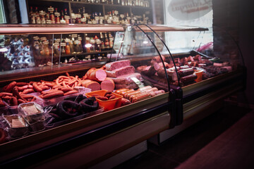 A row of shop windows with sausages and smoked meat. Ham and sausages with huge selection.