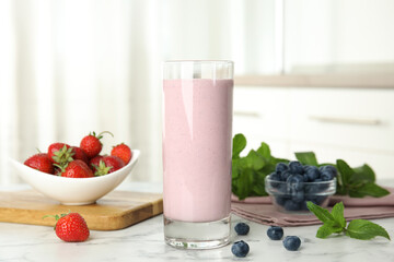 Tasty milk shake and berries on white marble table