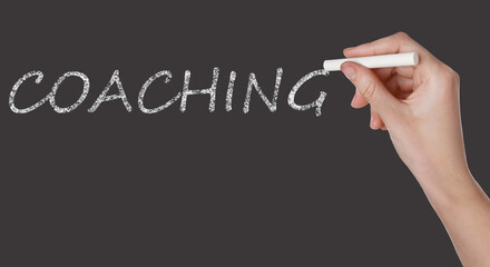 Business or life trainer writing word Coaching on blackboard, closeup. Banner design