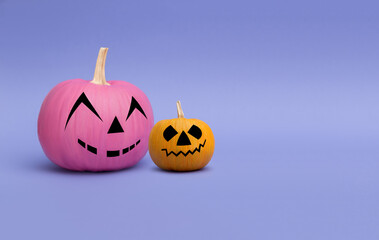 Two colorful pumpkins with smile on a purple background. Minimalist halloween concept.