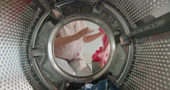 Housewife pulls multicolored laundry from washing machine