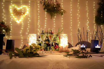 Champagne flutes on bridal table at wedding reception decorated with letters E and J with bokeh background