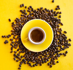 espresso on yellow surrounded by fresh roasted coffee beans