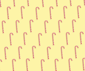 Pattern of Christmas candy canes on pale yellow background, top view