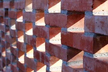 In selective focus a row of red brick wall with ventilation blocks pattern annd sunlight passng through a blocl space