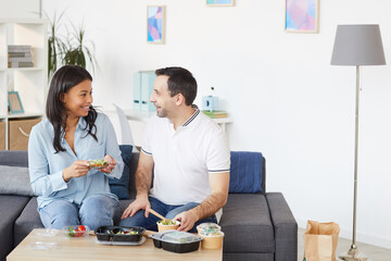 Portrait of smiling man and woman chatting cheerfully while enjoying takeout lunch in office or at home, copy space