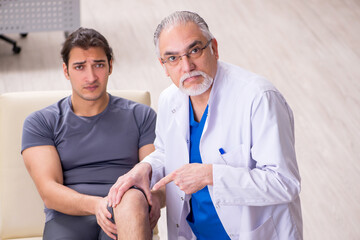 Obraz premium Young male patient visiting old doctor traumatologist