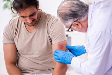 Obraz premium Young face injured man visiting experienced male doctor traumato