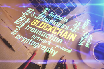 Blockchain theme hologram drawings over computer on the desktop background. Top view. Multi exposure. Concept of cryptoeconomy.