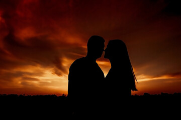 Fototapeta premium Silhouette of a loving couple on a background of dramatic sunset.