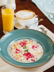 Vegetarian breakfast. Quinoa porridge with coconut milk with almonds and sushon raspberries. Nearby is cappuccino coffee and freshly squeezed orange juice. Menu for cafes and restaurants.