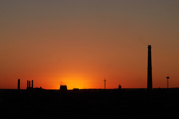 Fototapeta na wymiar Dramatic sunset on the sky and coal power plant factory. Petrochemical industrial plant. Oil and gas refinery tower in silhouette. Refinery for petroleum products