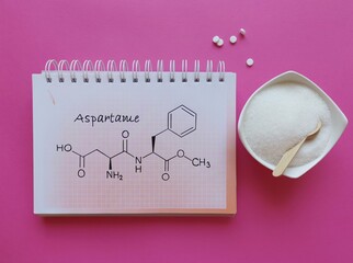 Structural chemical formula of aspartame molecule with artificial sweetener in bowl and white...
