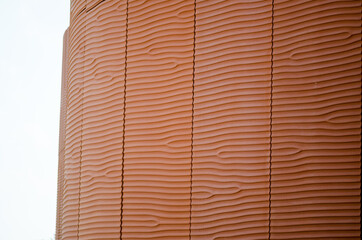 Background perspectives, which reflect the facade of a building with prefabricated panels of red concrete that recalls the silhouettes such as sand dunes in the desert smoothed by the wind, of the sea