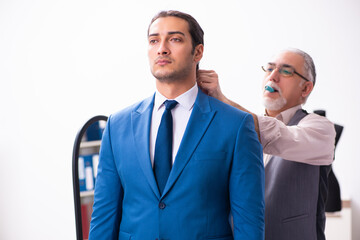 Young businessman visiting old male tailor