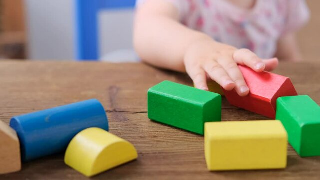 kid, baby builds towers and buildings from colored wooden figures, the concept of housing construction, mortgage, insurance, happy childhood, children's games, alpha generation