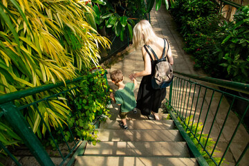 mother and son walk down the steps in the palm greenhouse