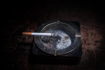 Ashtray and butts cigarettes on dark background. Selective focus