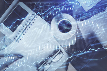 Double exposure of financial graph hologram over desktop with phone. Top view. Mobile trade platform concept.
