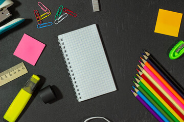 School supplies and notepad on a black background. Stationery on chalk board