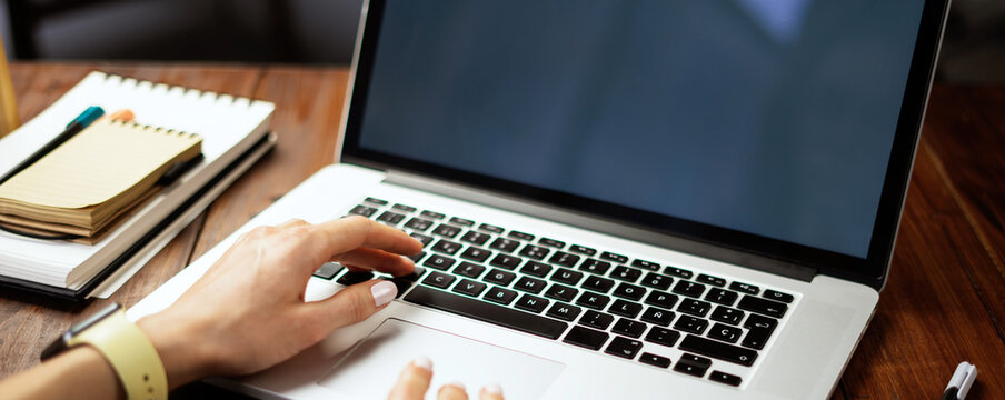 Closeup photo of female hands with a laptop. Female freelancer connecting to internet via computer. Blogger or journalist writing new article.