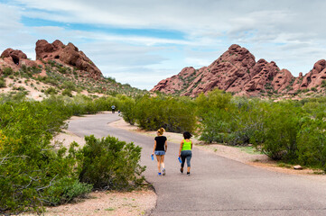 Two women walk the trail towards the sandstone buttes of Papago Park in Phoenix, Arizona.