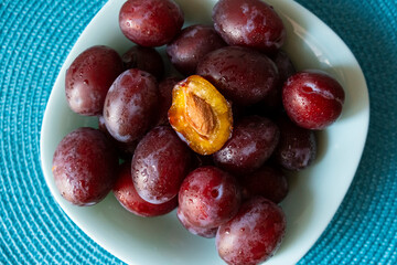 red plums on a plate. half a broken plum.