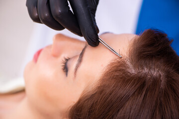 Young woman visiting male beautician in hair transplantation con