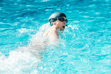 Fototapeta na wymiar Woman with swimming cap and goggles swimming in a pool