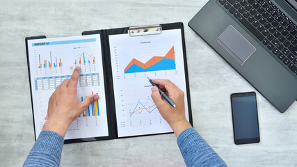 Top view of businessman checking reported profits on paper.