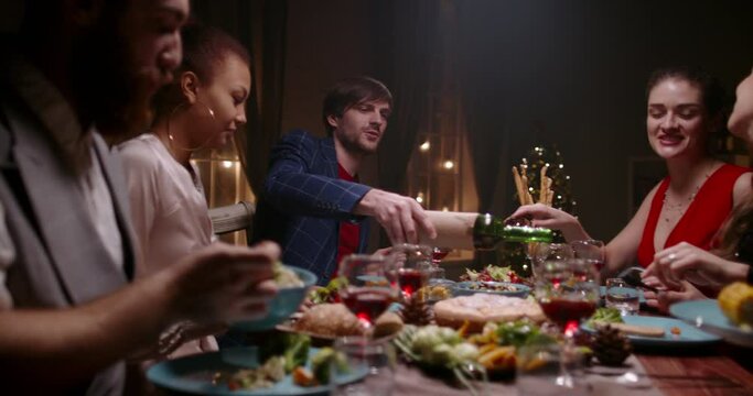 Six positive multiethnic friends celebrating christmas together. Cheerful students having a dinner, eating healthy vegan mediteranian food and talking 4k footage