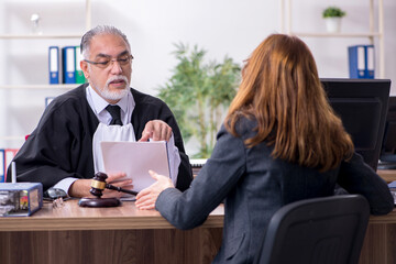 Old male judge and female client in the office
