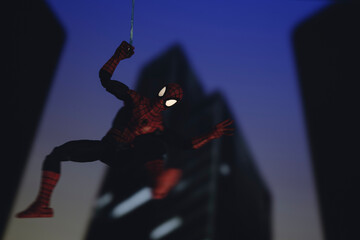 Fototapeta premium NEW YORK USA - AUGUST 9 2020: Marvel comics superhero Spiderman swinging from a web at night - Hasbro action figure