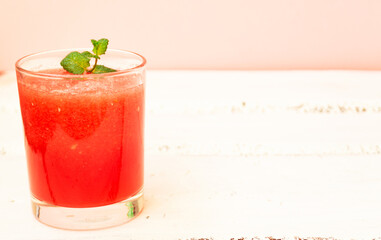 Delicious red watermelon juice with a sprig of green mint in a glass glass on a white background. Copy space. Summer food concept.