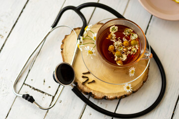 Decoction of chamomile, dried flower in flower tea and a phonendoscope, sliced lemon on a white...