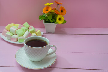 Coffee in white cup and marshmallows on pink wooden table. Morning breakfast, tenderness