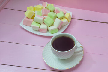 Coffee in white cup and assorted marshmallows on pink wooden tray. Morning breakfast, tenderness,...