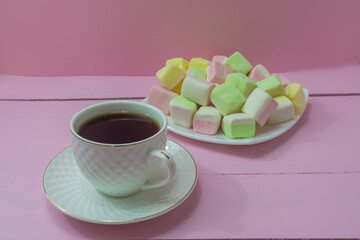 Fototapeta na wymiar Cup of coffee on pink wooden table and lot of marshmallows for breakfast. Tenderness in the morning, positive, good mood