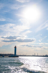 A beautiful lighthouse. View from the sea. Sun in the sky.