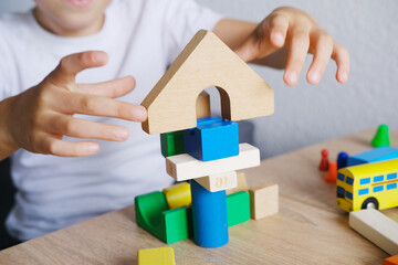 kid, boy builds towers and buildings from colored wooden figures, concept of housing construction,...